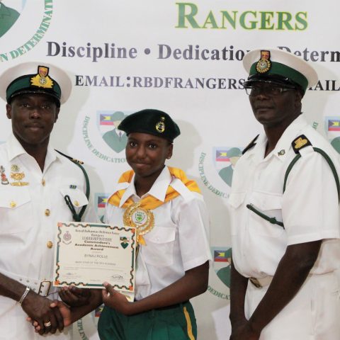 Bynaj Rolle of Mary Star Academy receiving the Commander Defence Force Academic Achievement Award at the RBDF Rangers Passing out Parade ceremony in Grand Bahama on May 11, 2019. Also shown are: Lieutenant Commander Johnson, the commanding officer of the RBDF Freeport Base and Rangers Operations Senior Rate, Chief Petty Officer Pedro Bain.